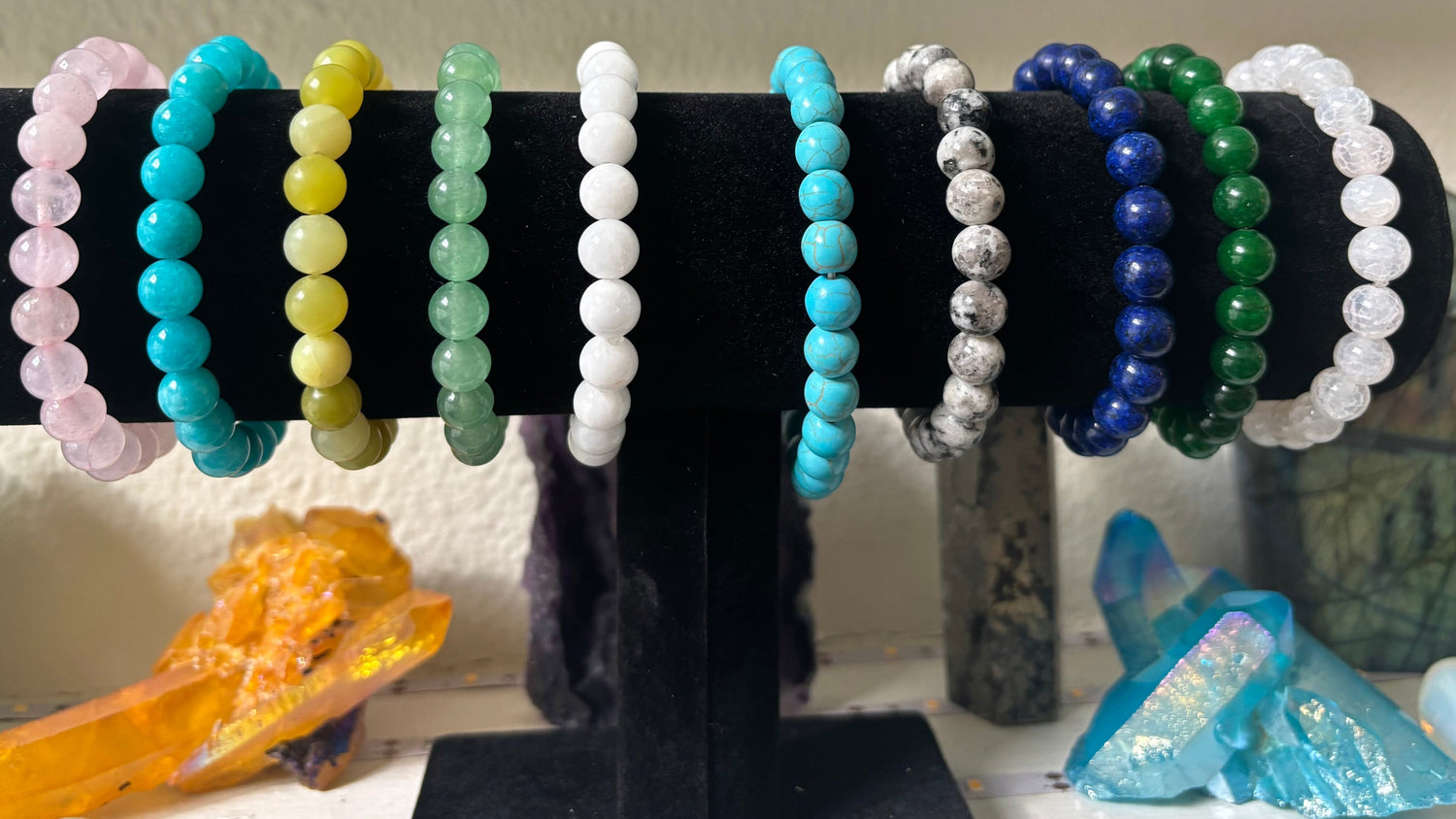 A collection of beaded bracelets displayed on a stand, featuring various colors including pink, green, blue, white, and purple.